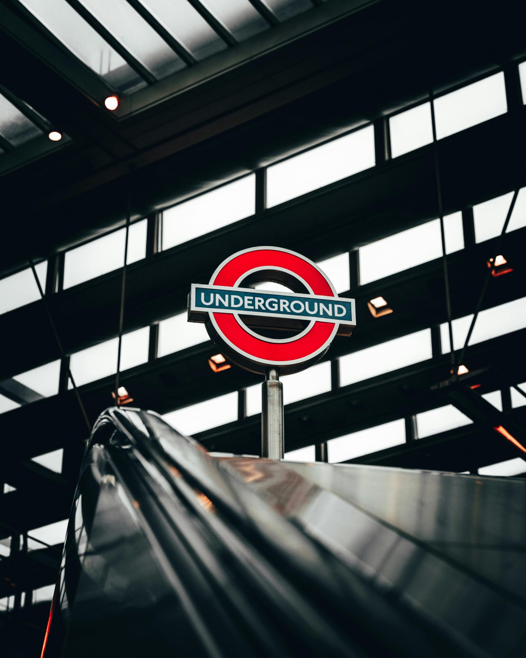 Iconic London Underground sign against a backdrop of modern architecture and steel beams.